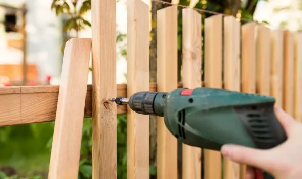 Builders Rodney fencing contractors using a drill to assemble a timber fence with precision.