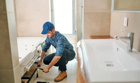 Builder fixing bathtub plumbing showcasing Builders Rodney bathroom renovations expertise