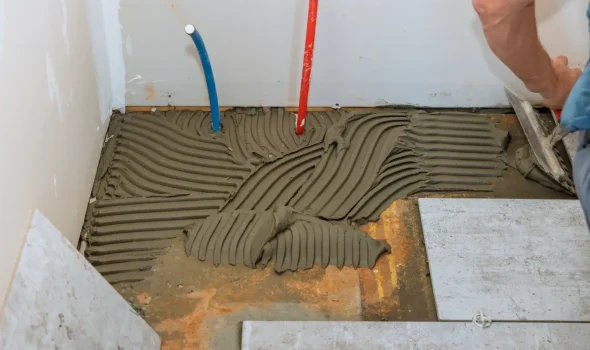Tiling floor with adhesive applied by Builders Rodney showcasing expert bathroom renovations craftsmanship